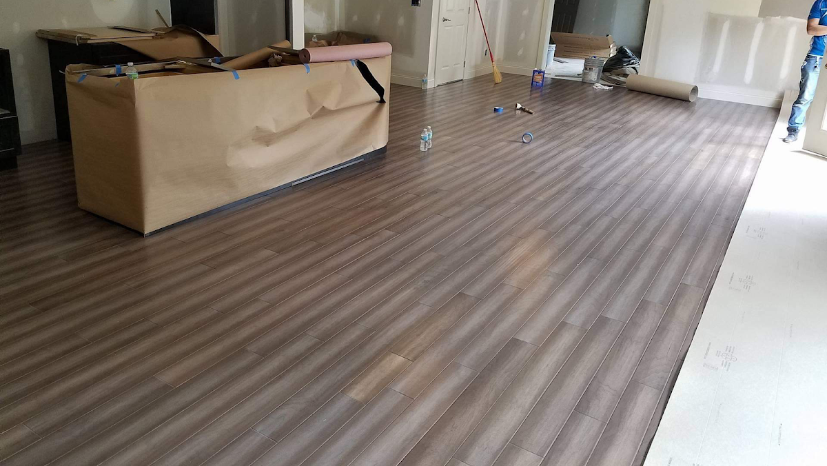 Large room mid-installation with new plank flooring and protective materials